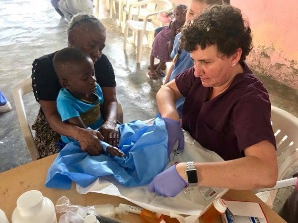 Dr. Feiler working on the hand of a child sitting on a woman's lap